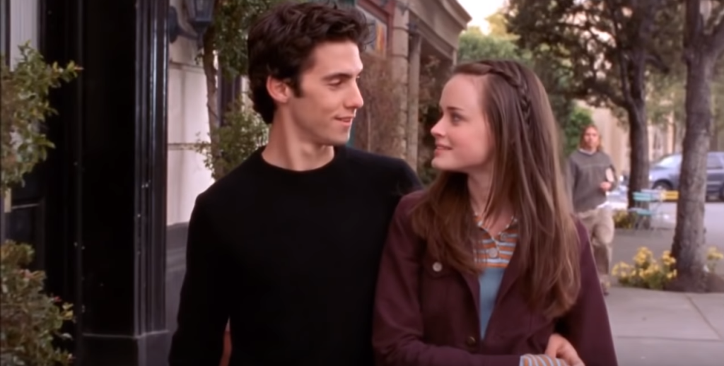 Rory Gilmore and Jess Mariano from the series 'Gilmore Girls' walk down the street in Stars Hollow and look into each others eyes.