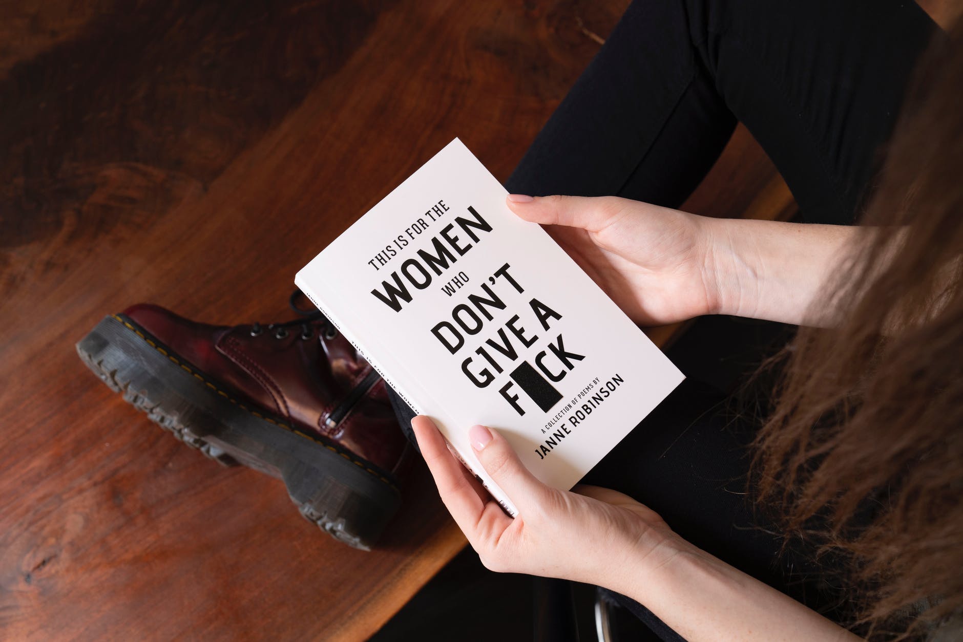A woman holds a book entitled "This is For the Women Who Don't Give a F**k".