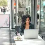 Woman starts her own blog on a laptop outside a café