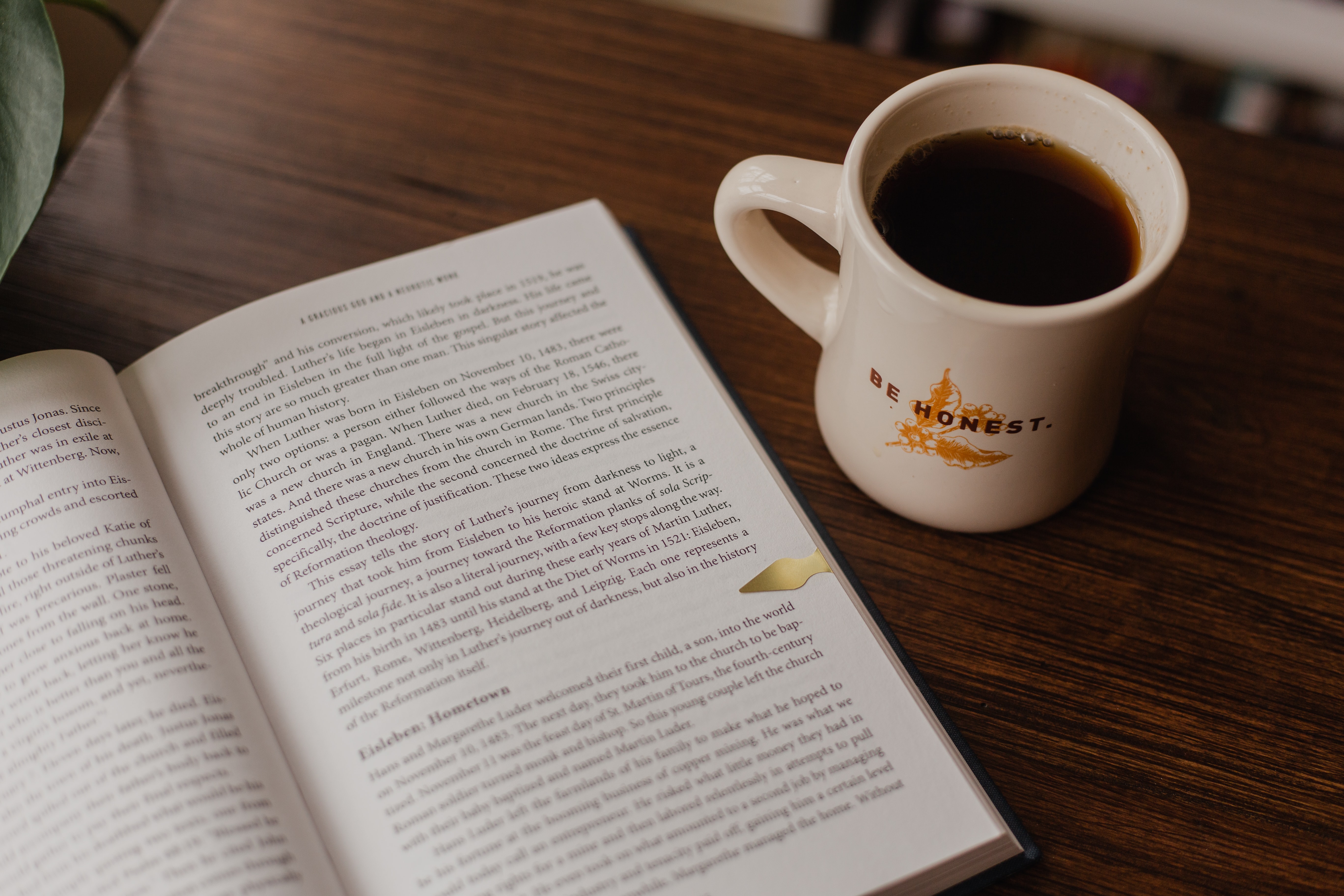 Open book with mug of coffee. The mug has "be honest" written on it