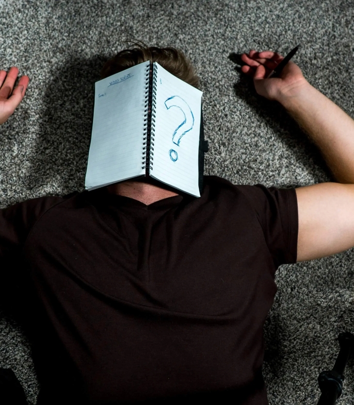 person laying on the floor with a notebook over the face